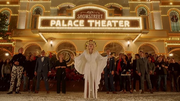 Dolly Parton and backup singers standing in front of a theatre in the snow