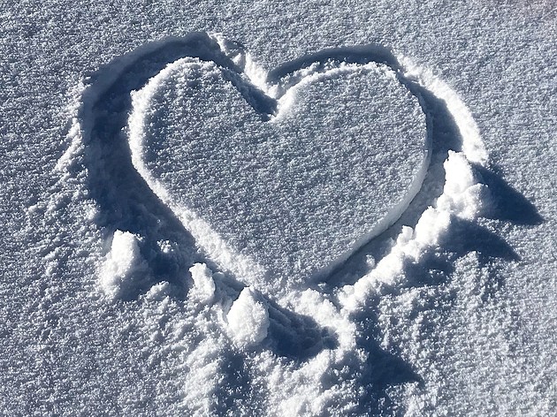 A heart shaped pattern painted in a white sunny snow field.